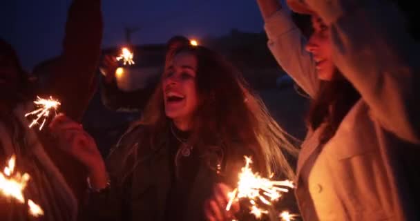 Groupe multi-ethnique d'amis tenant des étincelles sur la plage la nuit — Video