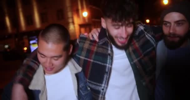 Jonge hipster mannelijke vrienden lopen 's nachts door de straat — Stockvideo