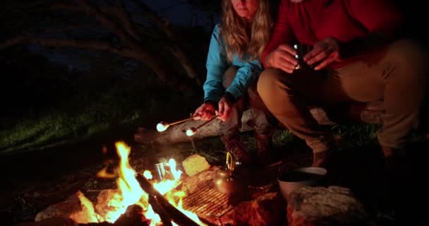Senior caucasian couple sitting together frying marshmallows by the bonfire — Stock Video