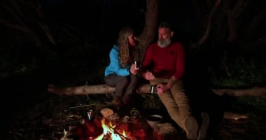 Kafkasyalı üst düzey bir çift birlikte oturup şenlik ateşinde çay içiyor.