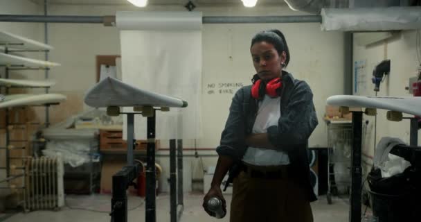Μαύρη γυναίκα κρατώντας σπρέι στέκεται στο εργαστήριο σανίδα του σερφ — Αρχείο Βίντεο