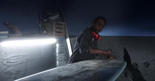 Fekete nő mérő szörfdeszka mérőszalaggal műhelyben — Stock videók