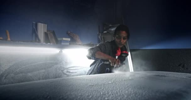 Черная женщина распыляет пыль с доски для серфинга в мастерской — стоковое видео