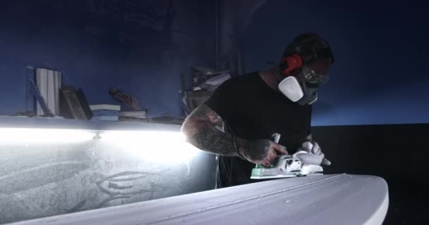 Hombre formando tabla de surf con lijadora eléctrica en taller — Vídeo de stock