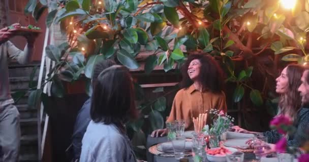 El hombre trae comida a la mesa para la comida con amigos multiétnicos — Vídeo de stock