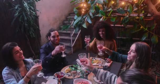 Πολυεθνικοί φίλοι και ζευγάρια που κάνουν πρόποση για το κρασί κατά τη διάρκεια του γεύματος στο αίθριο — Αρχείο Βίντεο