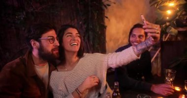 Kafkasyalı çift, veranda partisinde akıllı telefonlarıyla selfie çekiyor.