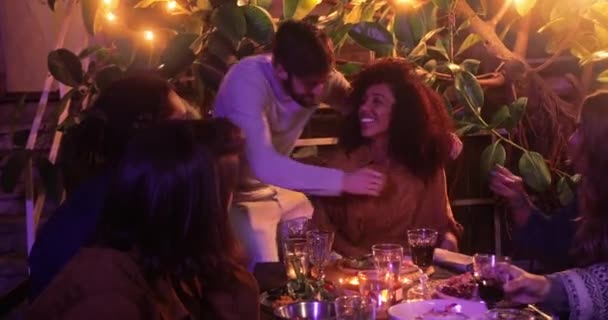 Close up man knuffelen zwart vrouw tijdens maaltijd met vrienden — Stockvideo