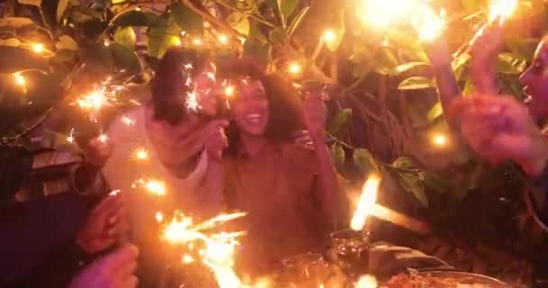 Woman hugging black friend while celebrating birthday meal with sparklers — Stock Video