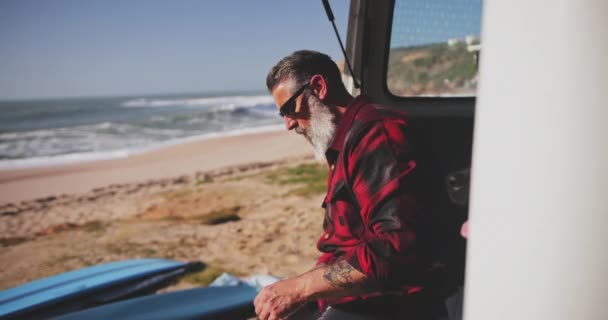 Senior man with dog sitting in van preparing to surf — Stock Video