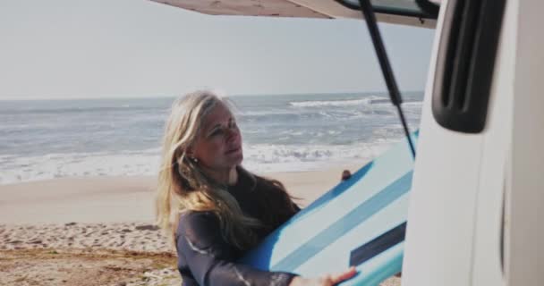 Senior όμορφη γυναίκα αφαίρεση σανίδα του σερφ από το βαν στην παραλία — Αρχείο Βίντεο