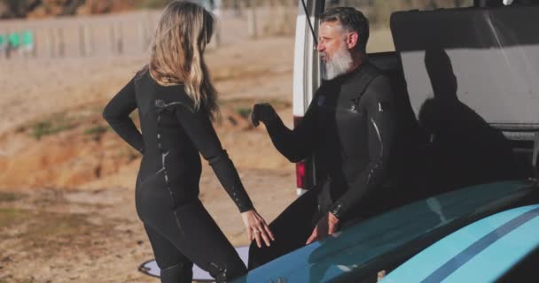 Dalgıç kıyafeti giyen yaşlı çift sörf yapmadan önce konuşuyor. — Stok video