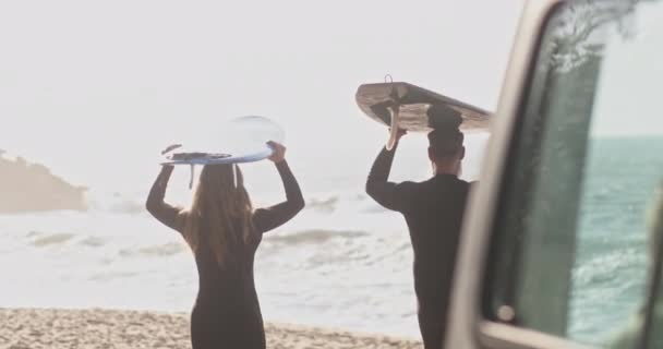 Primer plano vista trasera pareja de ancianos sosteniendo tablas de surf en la playa — Vídeo de stock