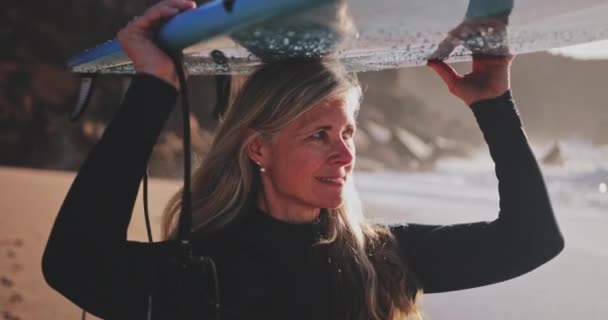 Cerca de la mujer mayor llevando tabla de surf en la playa — Vídeo de stock