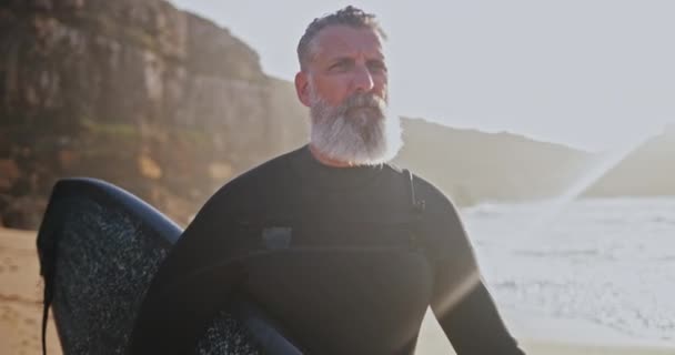 Fechar acima do homem bonito sênior que carrega a prancha de surf na praia — Vídeo de Stock