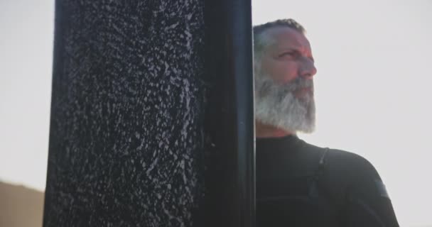 Großaufnahme Senior Mann hält Surfbrett am Strand — Stockvideo