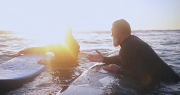 Senior man and woman surfing in the water at sunset — Stock Video