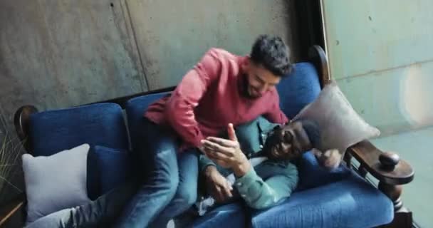 Amigos multiétnicos saltando uno encima del otro en el sofá — Vídeo de stock