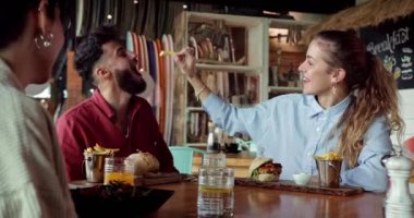 Genç sarışın kadın restoranda Frie 'yi orta doğulu bir adama yediriyor.
