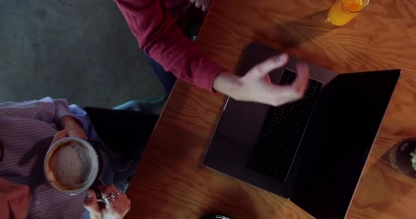 Top view close-up of young students using laptop at cafe — Stock Video