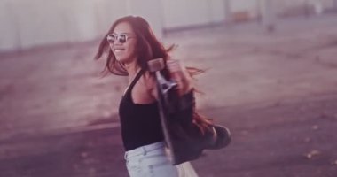 Şehirde dönen kaykaylı mutlu Asyalı kadın