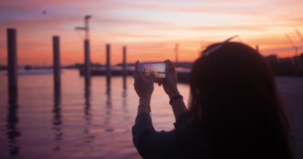Hipster mujer tomando fotos de paisaje en el teléfono inteligente al atardecer — Vídeo de stock