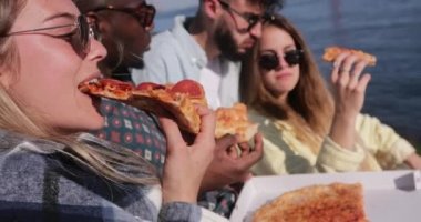 Nehir kenarında pizza yiyen çok ırklı arkadaşlara yakın.