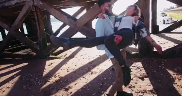 Mann aus dem Nahen Osten hält blonde Frau im Arm, die sich an Seebrücke dreht — Stockvideo