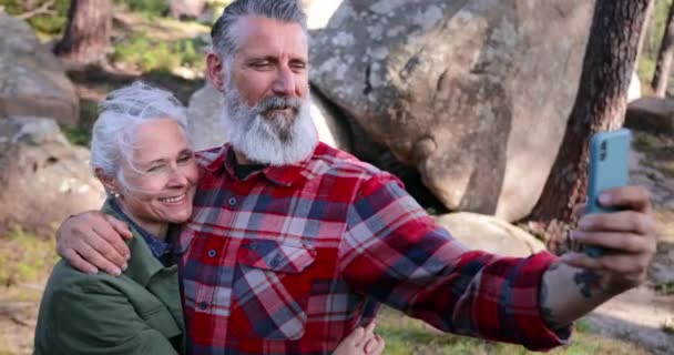Закройте пожилую пару, делающую селфи со смартфоном в лесу — стоковое видео
