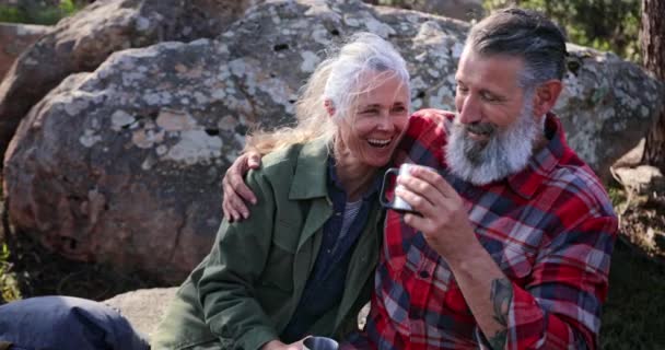 Närbild senior par skrattar dricka ur koppar i skogen — Stockvideo