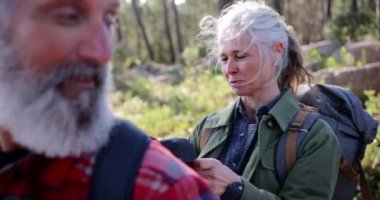 Son sınıf öğrencisi kadın ormanda sırt çantasını kontrol ediyor.