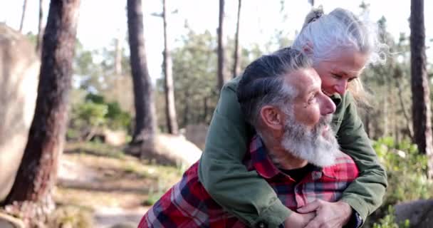 Närbild senior kvinna piggyback senior man i skogen — Stockvideo