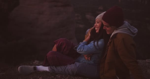 Çok ırklı hipster çifti kucaklıyor ve dağın tepesinde oturuyor. — Stok video