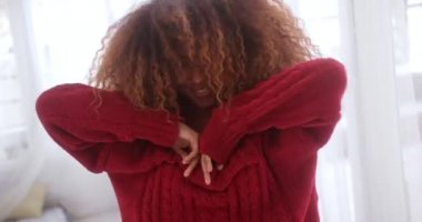 Kırmızı kazak giyen siyah kadın kazağıyla oynuyor.