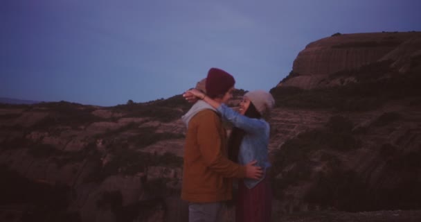 Щаслива багатоетнічна пара хіпстерів обіймає і цілує на вершині гори — стокове відео