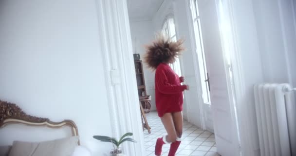 Black woman wearing reindeer antlers headband dancing around the house — Stock Video