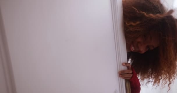 Donna nera che indossa maglione rosso sbirciando da dietro una porta — Video Stock