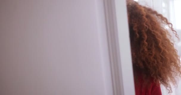 Musta nainen kurkistaa oven takaa hymyillen ja nauraen — kuvapankkivideo