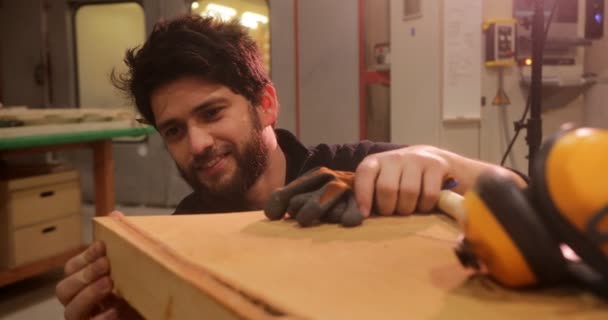 Gros plan de l'homme en atelier vérifiant la planche de bois — Video