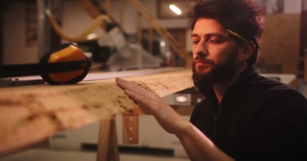 Gros plan de l'homme en atelier vérifiant la planche de bois — Video