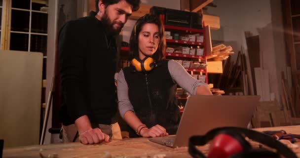 Man och kvinna i snickarverkstad med bärbar dator — Stockvideo