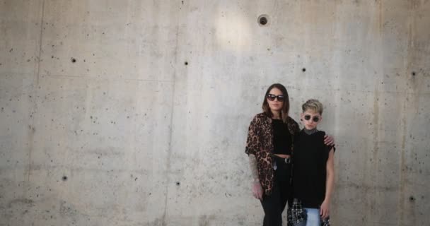 Lesbian couple standing next to concrete wall embracing each other — Stock Video