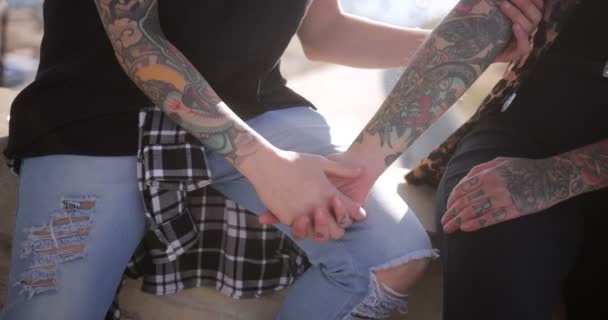 Крупним планом лесбійська пара сидить разом тримаючи руки на відкритому повітрі — стокове відео