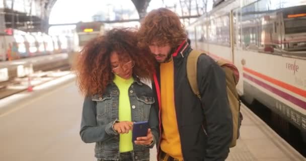 Giovane coppia multietnica utilizzando lo smartphone alla stazione ferroviaria — Video Stock