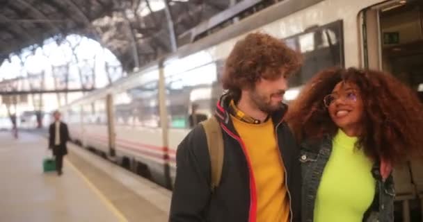Мультиетнічна пара їде з поїзда і ходить разом на вокзалі. — стокове відео