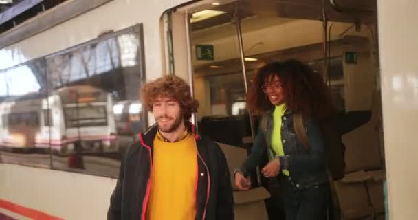 Multi-εθνοτική ζευγάρι αφήνοντας το τρένο φίλη piggybacking φίλο στο σιδηροδρομικό σταθμό — Αρχείο Βίντεο