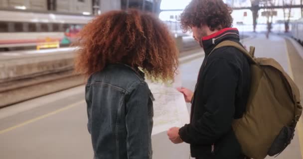 Casal multi-étnico verificando mapa na plataforma de trem na estação de trem — Vídeo de Stock