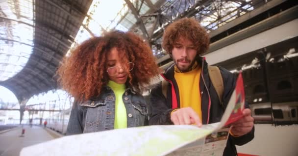 Multietnický pár kontrolující mapu na nástupišti na vlakovém nádraží — Stock video
