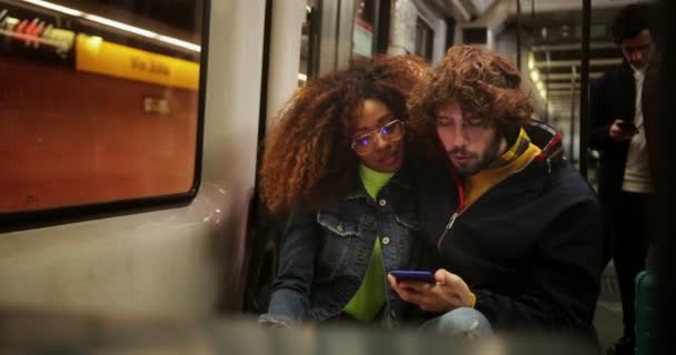 Felice giovane coppia multietnica utilizzando smartphone mentre seduto in treno — Video Stock