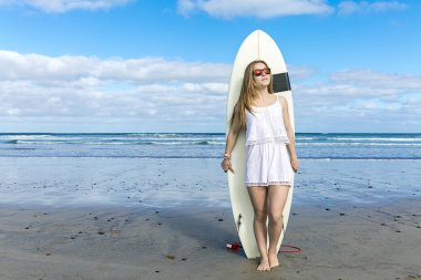 Genç kadın sörf tahtası üzerinde eğilir